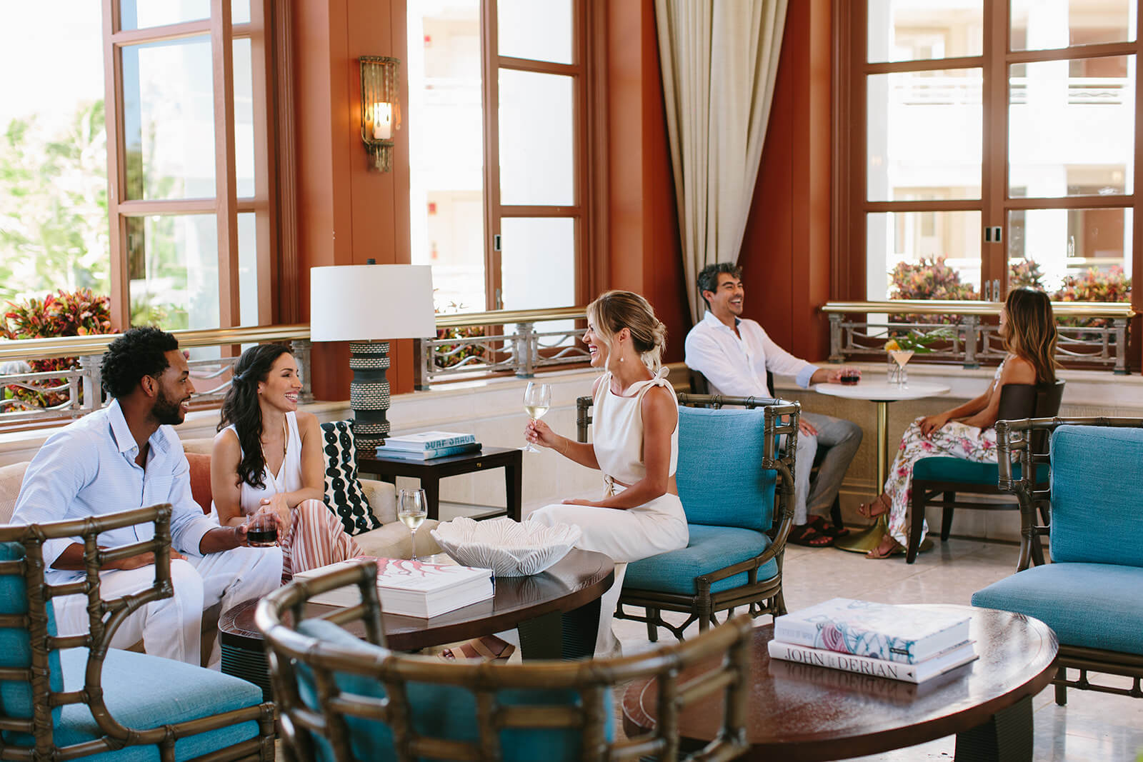 a group of people sit on comfortable lounge seating facing each other in a large open room 