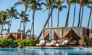 Two canopied poolside cabanas under a row of palm trees