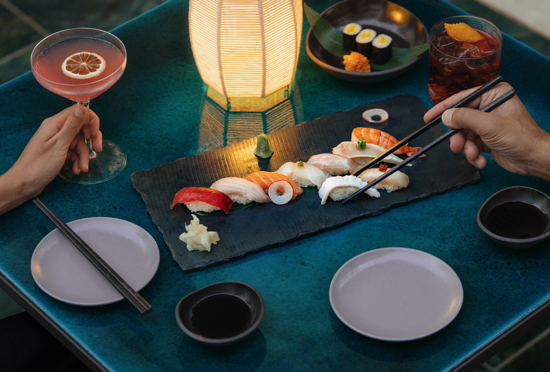 An elegant plate of sushi on a lantern-illuminated table